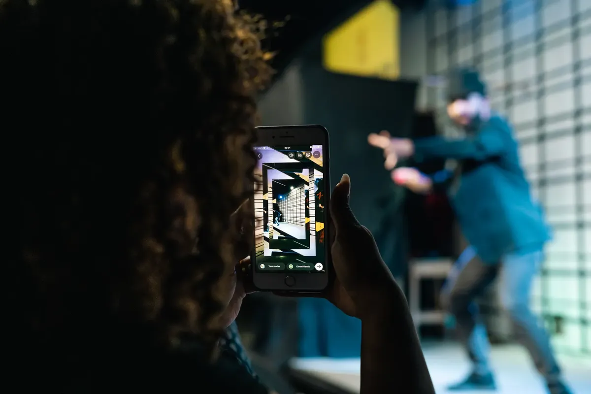 A person takes a photo of a live performance using a smartphone, highlighting modern technology in event capturing.